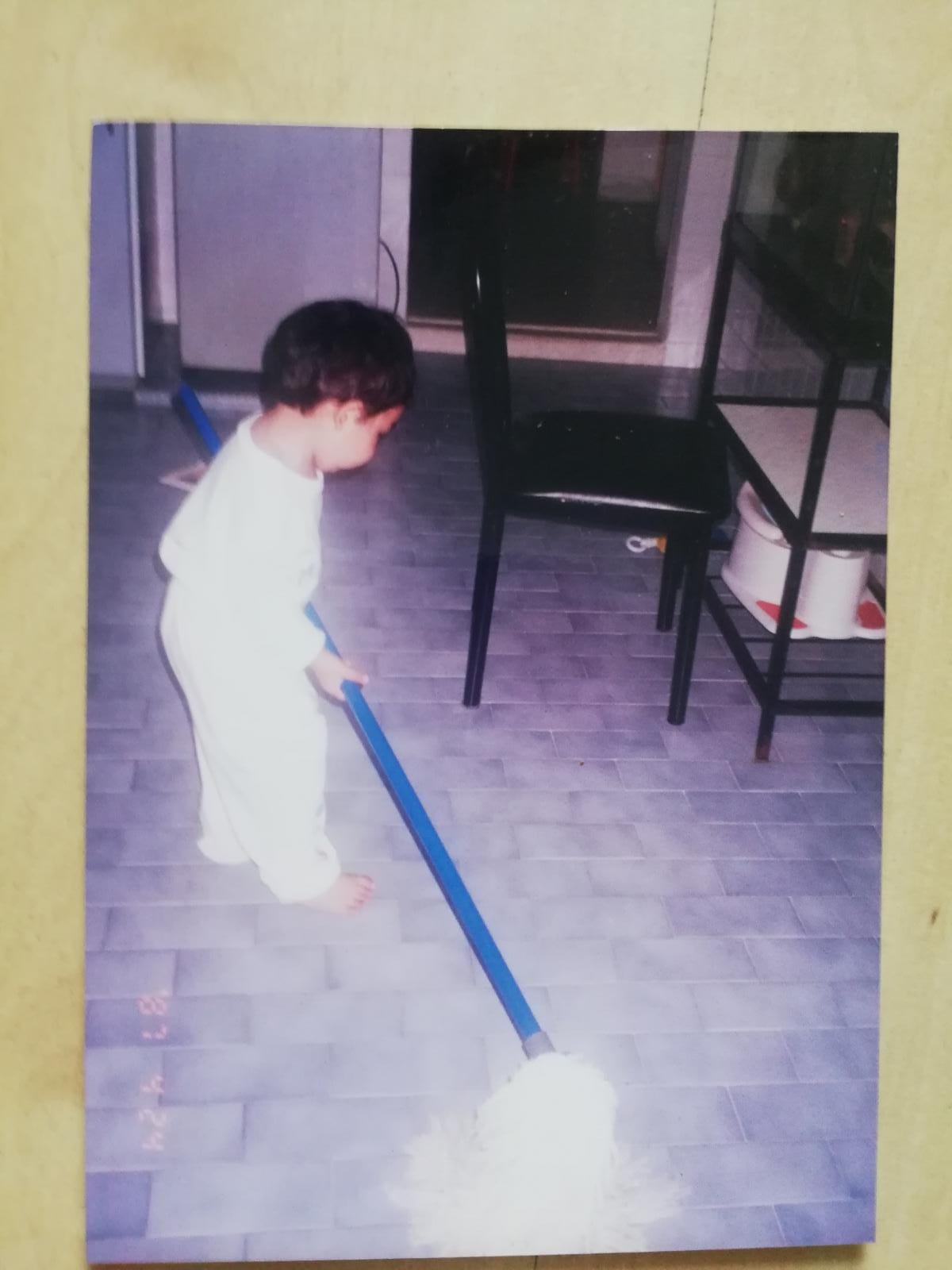 The writer as a young child mopping the floor at home