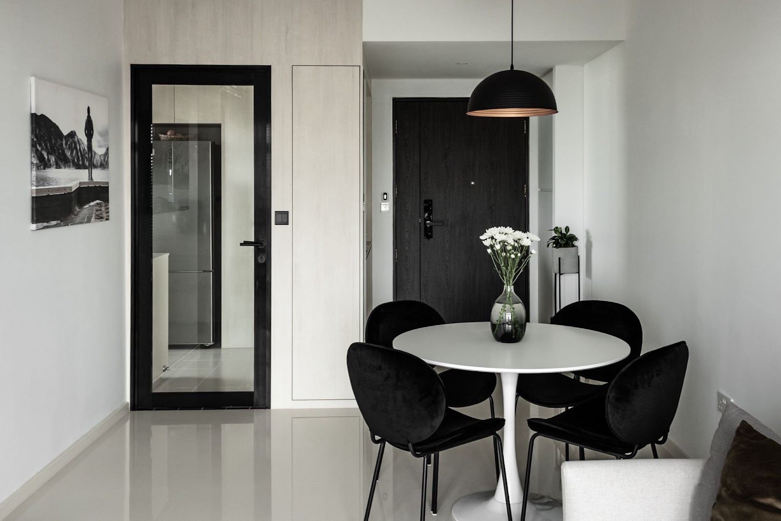 Black and white dining nook with a round white table, black chairs and a black pendant lamp