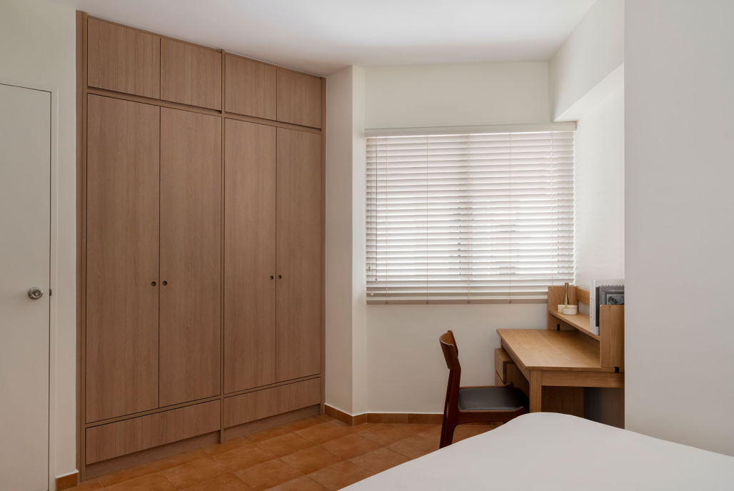 Bedroom with full-height wooden wardrobes and a study desk by the window