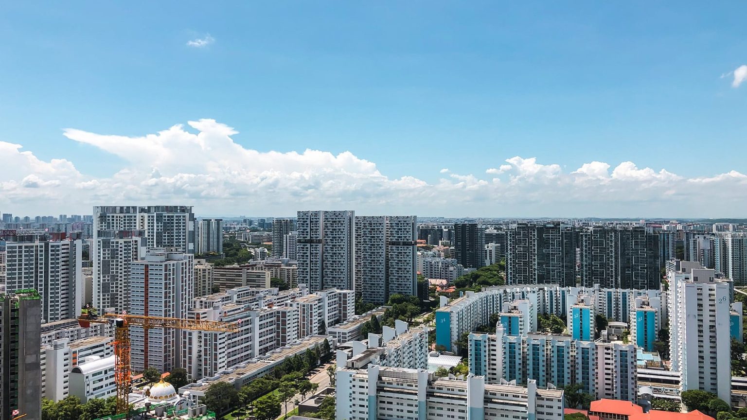 Highrise residential blocks with construction crane against a blue sky with white clouds