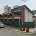 Two-storey conserved brick and white building under renovation near residential blocks with vehicles parked on the street
