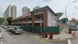 Two-storey conserved brick and white building under renovation near residential blocks with vehicles parked on the street