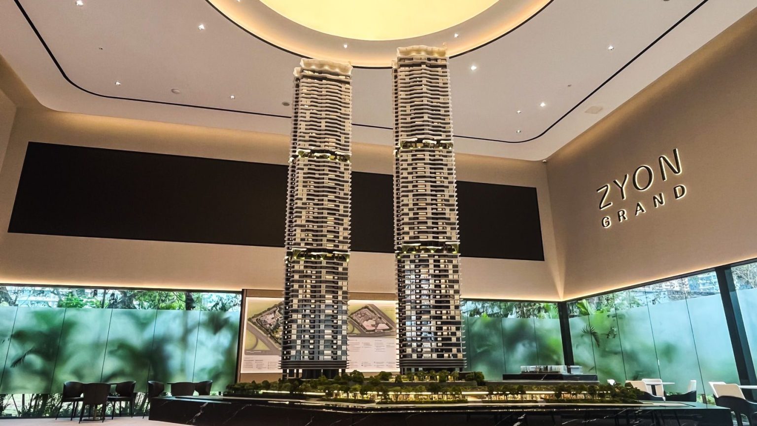 Scale model of Zyon Grand residential towers displayed in a sales gallery with seating area