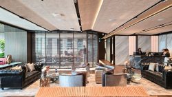 Residential lounge with leather sofas, metal armchairs, glass tables and a reception desk behind a glass partition