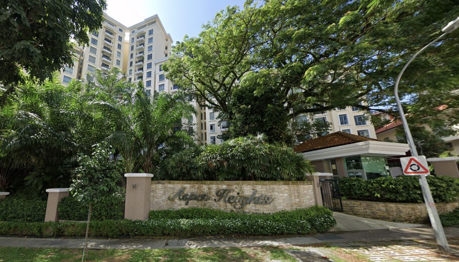 Aspen Heights residential block with cream-coloured walls, surrounded by trees and greenery