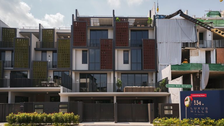 Modern three-storey terrace houses under construction with decorative latticed panels and black fencing