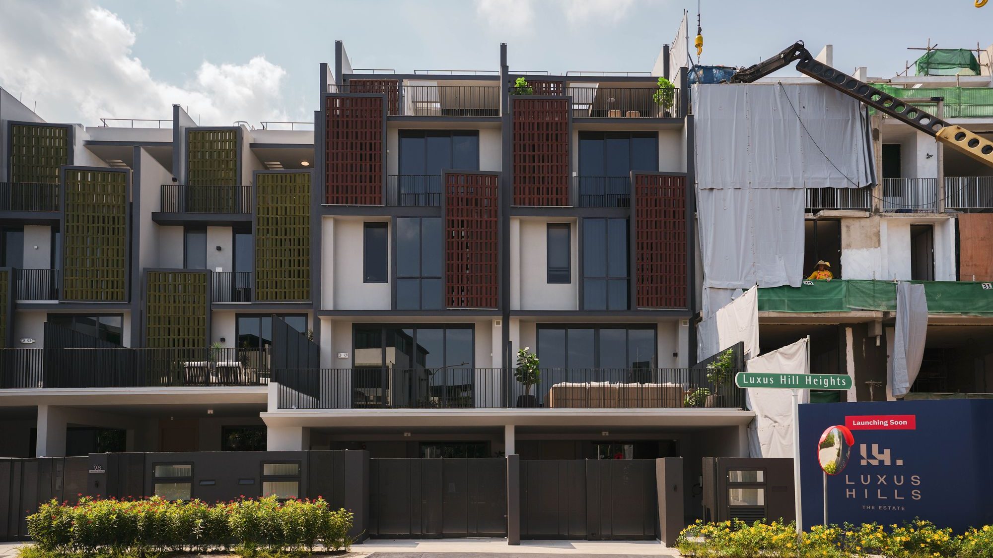 Modern three-storey terrace houses under construction with decorative latticed panels and black fencing
