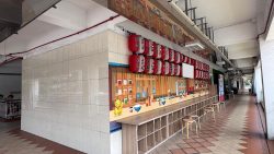Covered walkway with tiled floor, tiled wall, mural of kitchen utensils, red and white lanterns, stools and cubby shelves