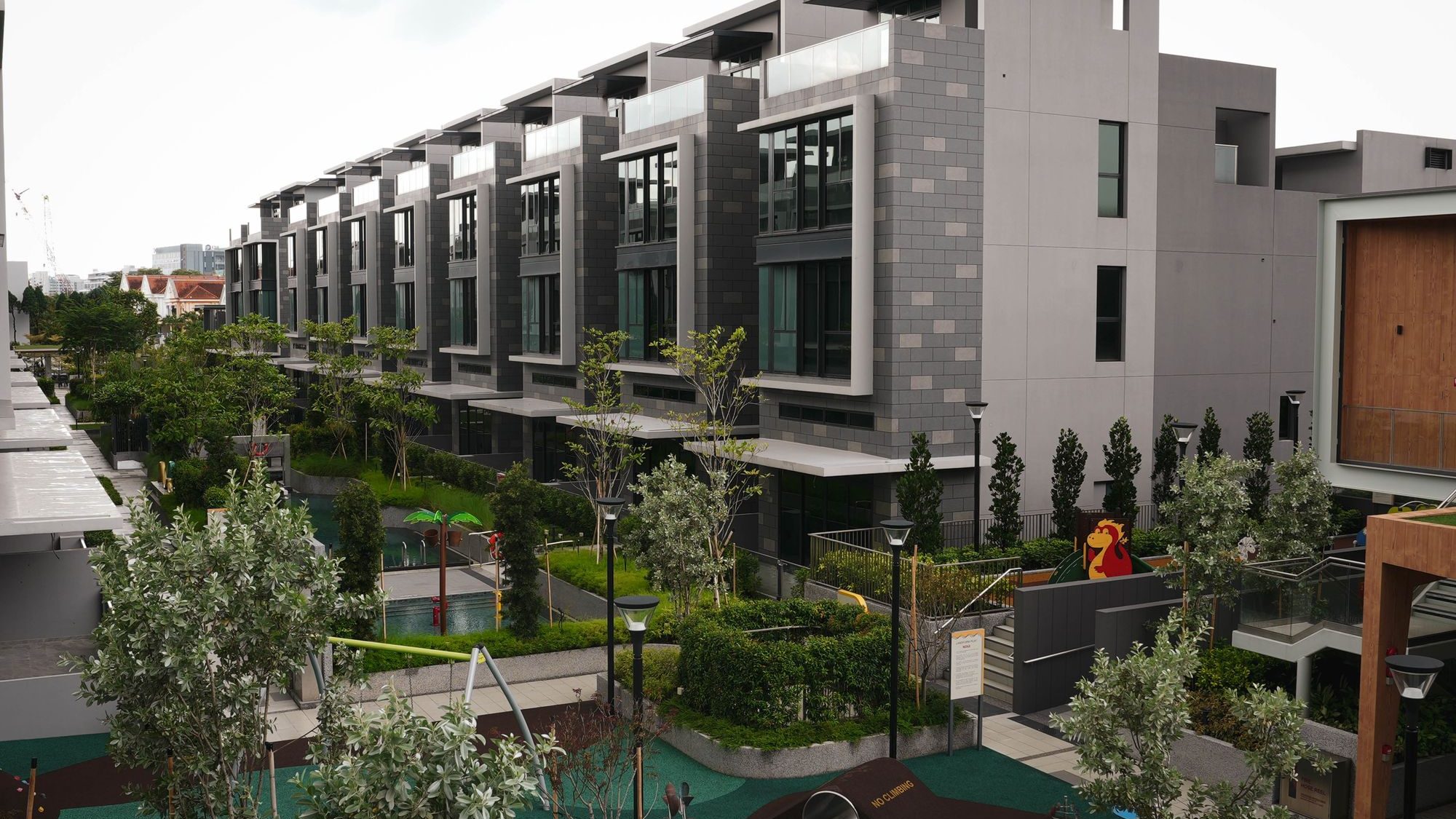 Modern apartment blocks with large windows next to a landscaped garden and playground area