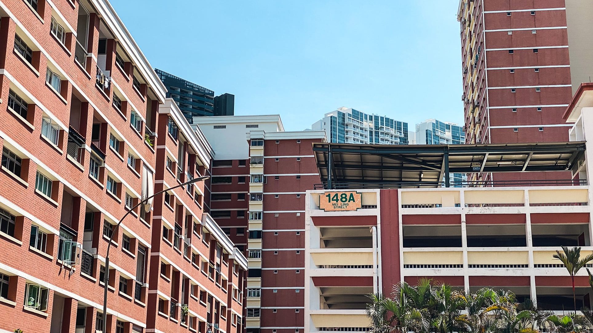 Red and white HDB blocks at 148A Mei Ling Street with tropical greenery under blue sky