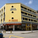 Yellow Verdun House commercial building with ground-floor shops and parked cars on the street
