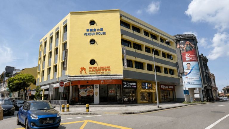 Yellow Verdun House commercial building with ground-floor shops and parked cars on the street