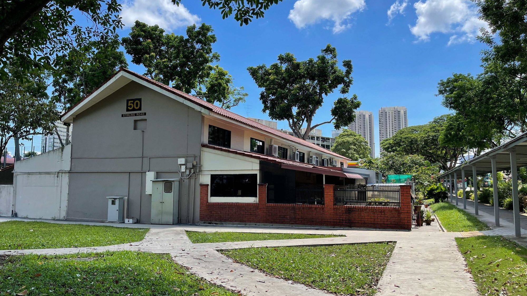 Single-storey terrace house with red brick wall and pitched roof at 50 Stirling Road amid trees and walkway