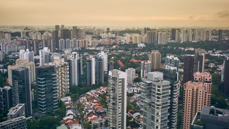 High-rise residential buildings and low-rise houses surrounded by greenery under an overcast sky