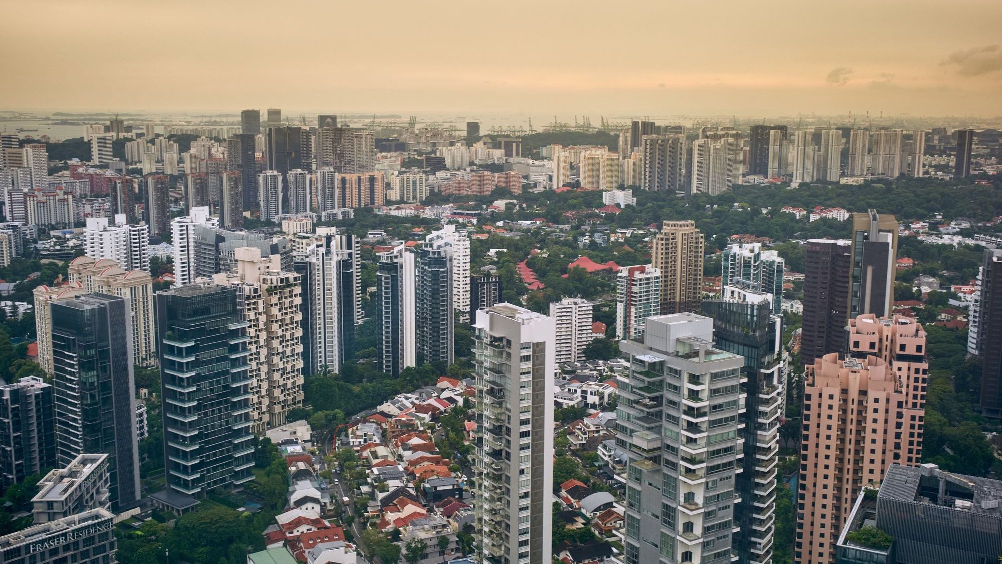 High-rise residential buildings and low-rise houses surrounded by greenery under an overcast sky