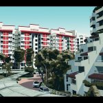 Red and white HDB blocks with trees and cars along a curved driveway in foreground