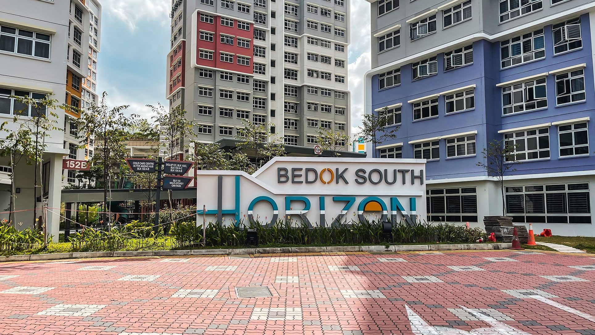 Bedok South Horizon signboard with residential blocks and greenery behind on a sunny day