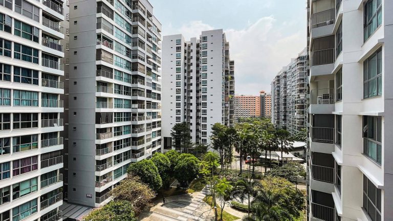 High-rise residential blocks surrounding a landscaped garden with trees and walking paths in a sunny setting
