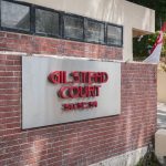 Gilstead Court sign with house numbers 50, 52, 54 on a brick wall near a gated driveway and Singapore flag