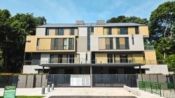 Modern landed homes with wooden panel exterior and gated entrance surrounded by trees