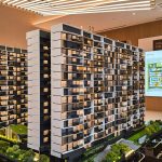 Scale model of a multi-storey apartment complex with a digital site plan display in a showroom
