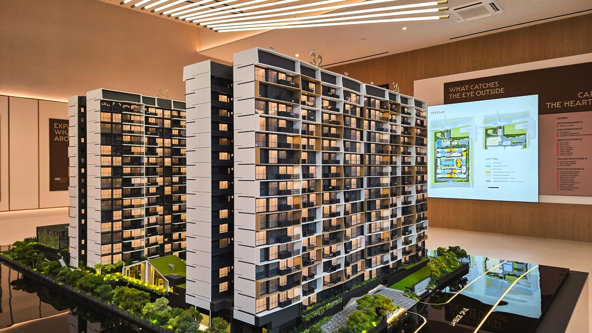 Scale model of a multi-storey apartment complex with a digital site plan display in a showroom