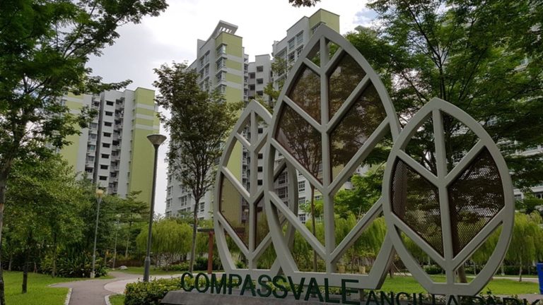 Compassvale Ancilla residential blocks with leaf-shaped metal structures and surrounding trees in the foreground