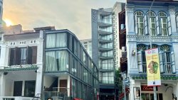 Mixed row of modern and conserved shophouses with a tall narrow apartment block named Cove behind them
