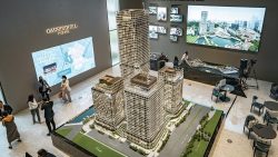 Model of CanningHill Piers residential blocks in a sales gallery with visitors and digital displays on walls