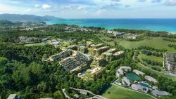 Apartment blocks surrounded by greenery with the sea and mountains in the background