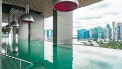 Infinity pool at South Beach Residences with a view of the city skyline and Marina Bay Sands in the background