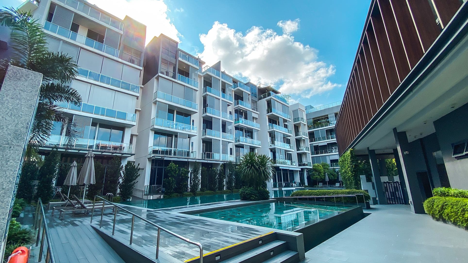 Robin Residences apartment blocks with swimming pool, sun loungers and landscaped greenery under a blue sky