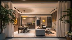 Open plan living and dining area with modern furniture, pendant lights, and large potted plants at Sloane Residences