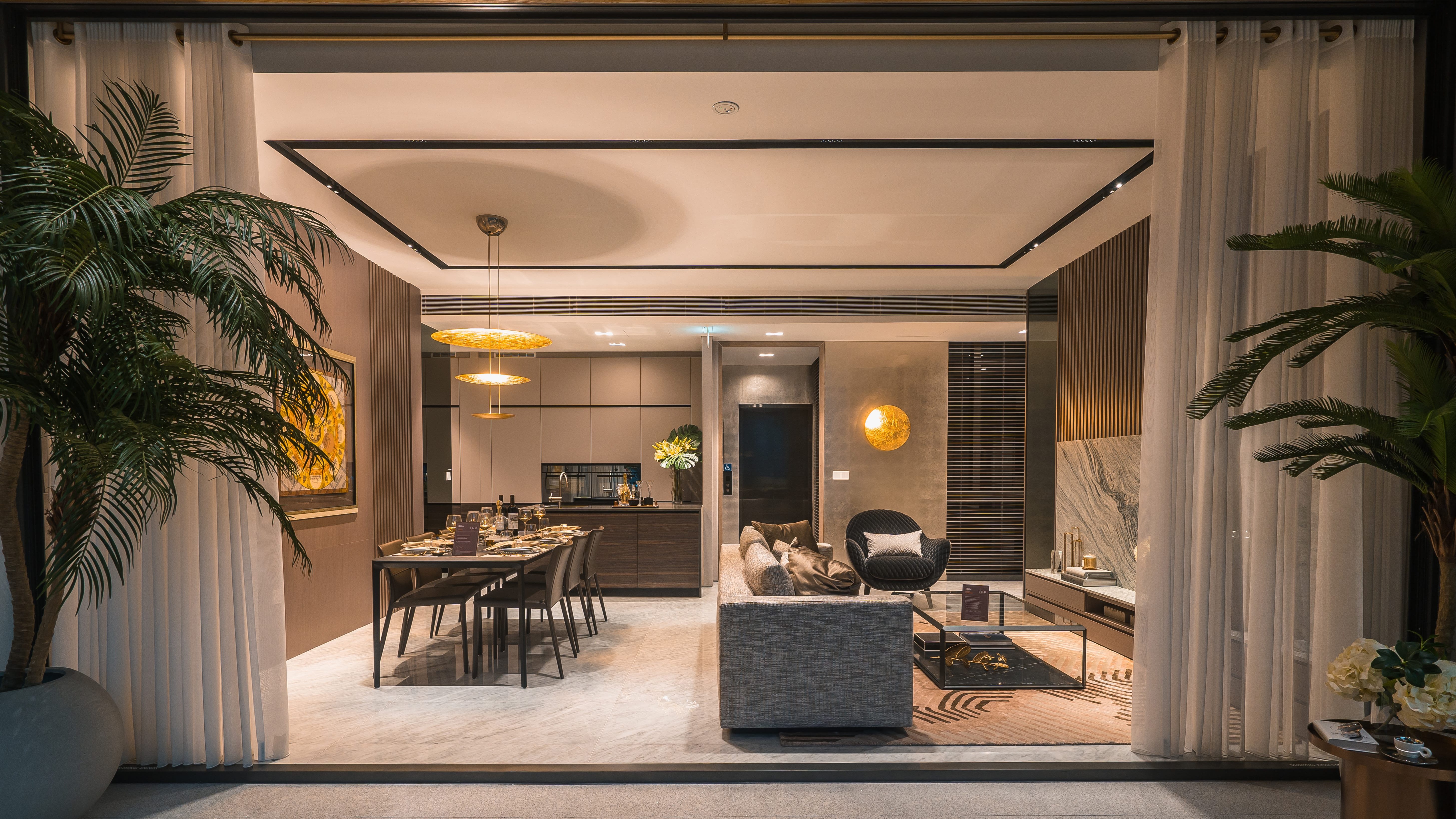 Open plan living and dining area with modern furniture, pendant lights, and large potted plants at Sloane Residences