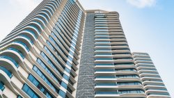 Trilight apartment blocks with curved balconies and blue glass windows against a clear sky