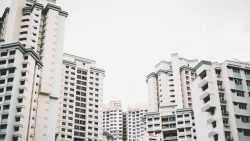 Tall white residential apartment blocks with balconies and air-conditioning units under an overcast sky
