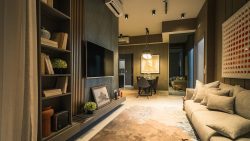 Living room with beige sofa, wall-mounted TV, bookshelf and dining area at Ola EC showflat