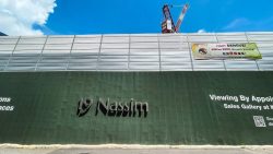 Sales gallery hoarding for 19 Nassim with mosquito prevention banner and construction crane behind it