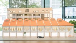 Scale model of Atlassia showing a row of shophouse-style townhouses with orange roofs and a black car in front