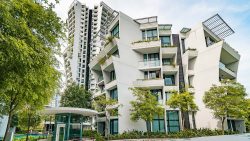 The Crest residential blocks with angular balconies, glass railings, plants, and surrounding greenery under a blue sky