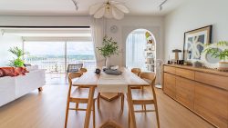 Dining area with wooden table and chairs, sideboard with decor, and living room with balcony view