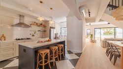 Kitchen with white cabinets, stainless steel appliances, island with stools, and adjoining dining area with balcony view