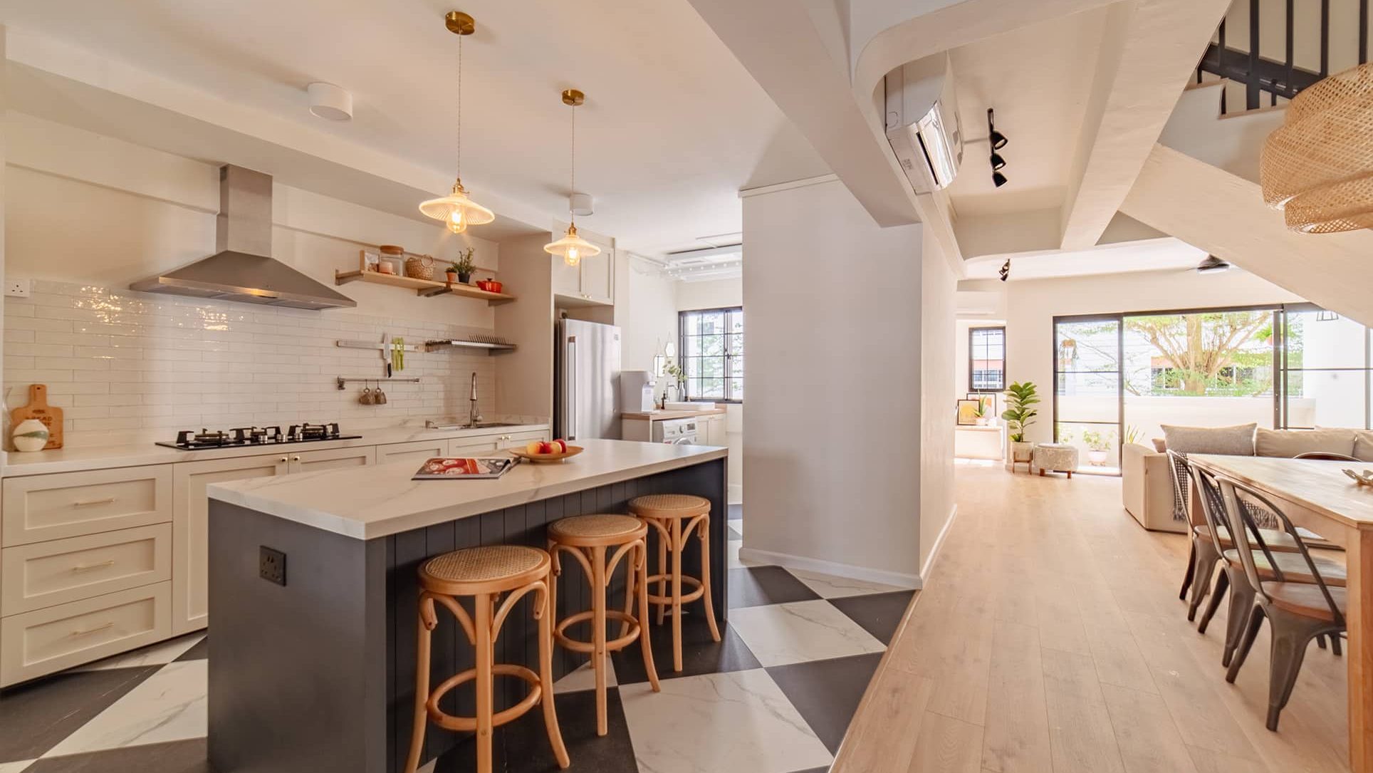 Kitchen with white cabinets, stainless steel appliances, island with stools, and adjoining dining area with balcony view