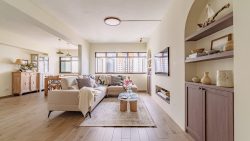Living room with beige sectional sofa, wooden coffee table, built-in shelves, and dining area behind