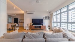 Living room with grey sofa, large TV on wooden console, dining area, and large windows with city views