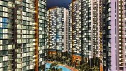 High-rise apartment blocks surrounding a landscaped pool area with trees and loungers at dusk