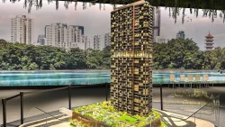 J'den condominium scale model with illuminated units and green rooftop facilities in sales gallery with cityscape backdrop