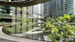 Curved walkway with railing overlooking water features and lush tropical plants in a modern mixed-use development