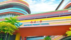 Nanyang Primary School building with coloured stripes across the facade and greenery in front