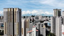 High-rise residential blocks with yellow and beige accents under a partly cloudy sky in an urban area